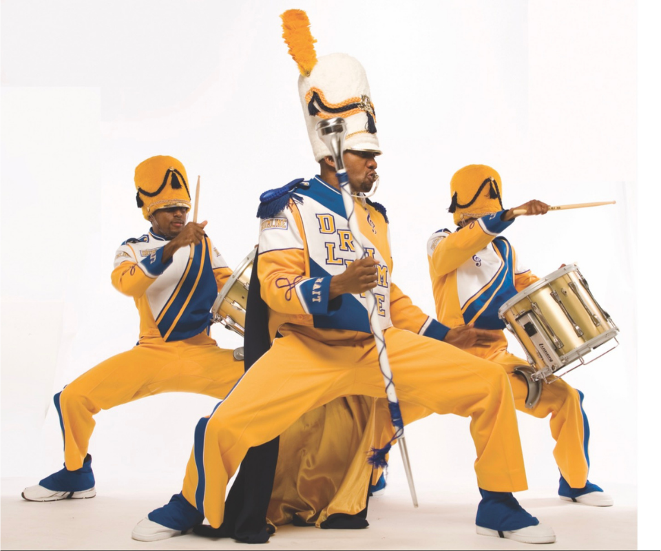 Marching band drumline and horn players performing in full uniform